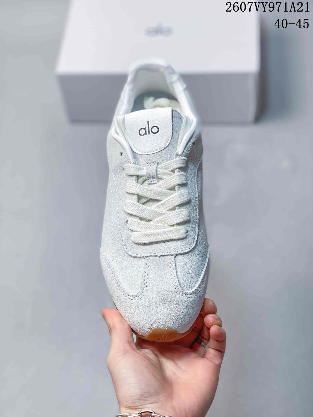 Top view of the white sneaker showing the Alo tongue logo, white laces, and stitched toe panels.