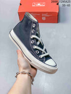 Angled side view of a navy Converse high-top sneaker with white laces, white rubber toe cap and textured outsole.