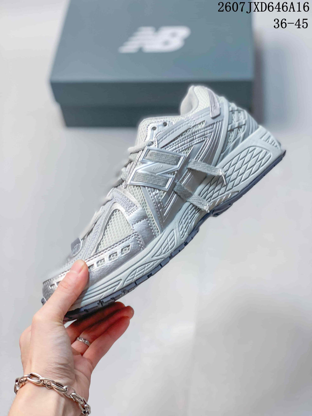 Side profile of a light gray and white New Balance 1906A sneaker with layered panel details.