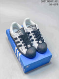 Pair of white and black adidas Superstar Supermodified sneakers displayed on a blue shoebox.