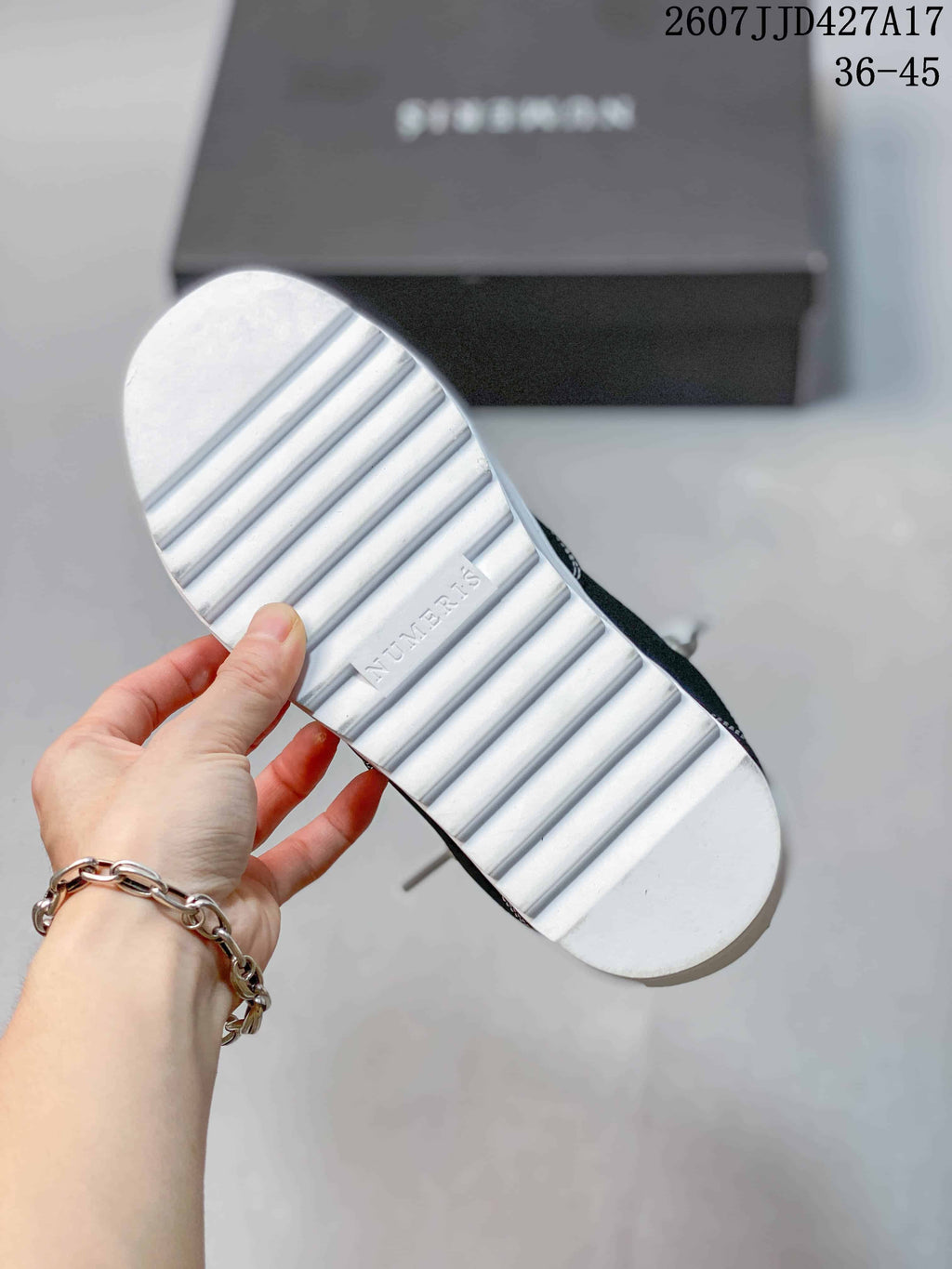 Underside of a Numeris sneaker showing the white ridged outsole and embossed branding.