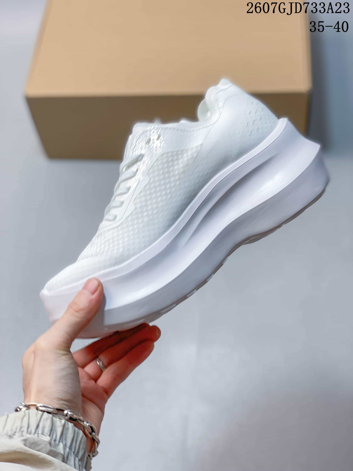 Side profile of the white low-top sneaker showing the textured upper, lace construction, and raised sculpted sole.