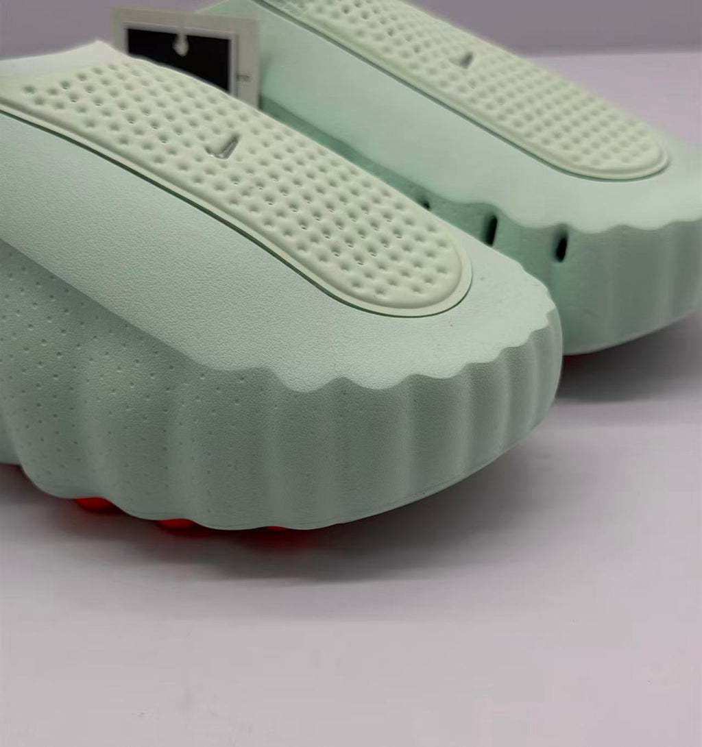 Close-up of the perforated upper panel and wavy edge of the light green slide sole.