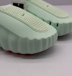 Close-up of the perforated upper panel and wavy edge of the light green slide sole.