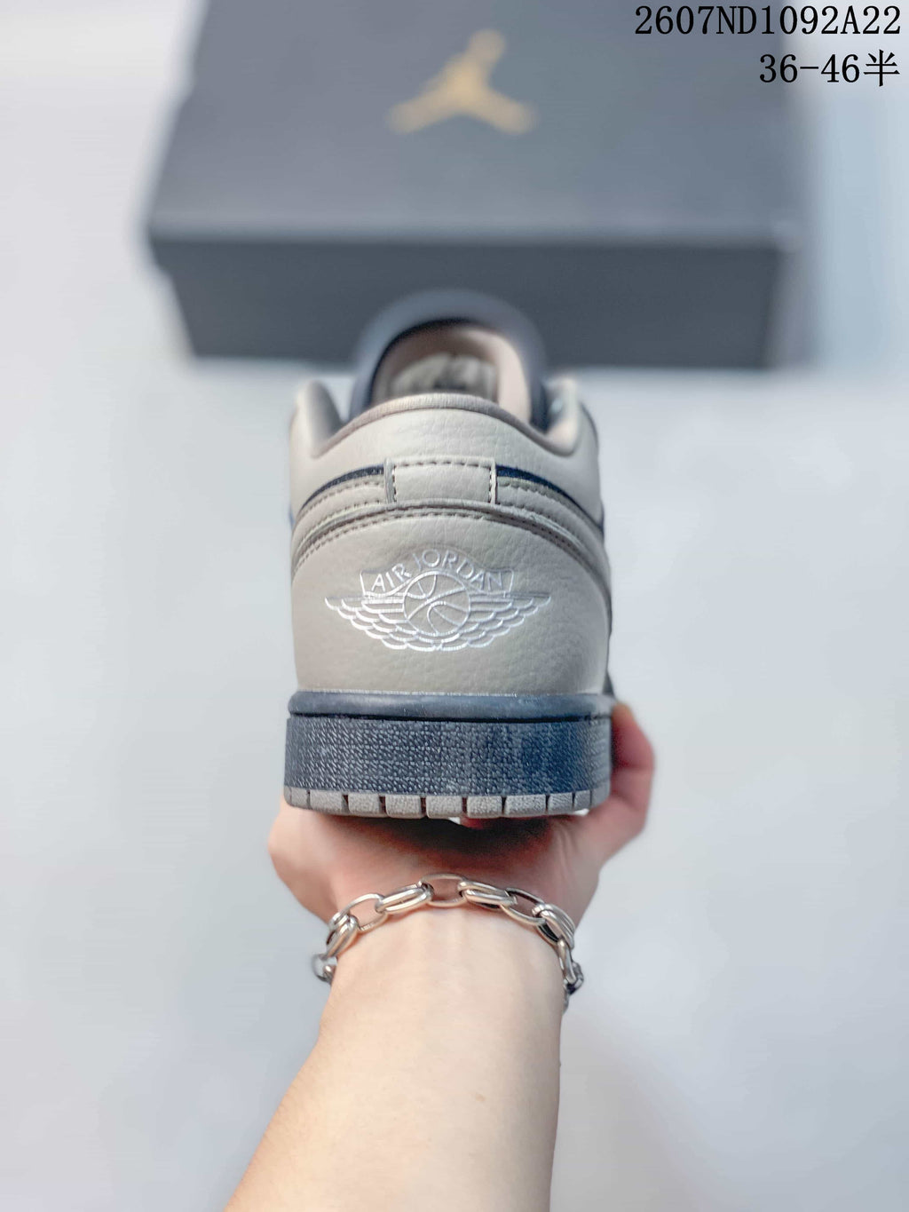 Rear view of a gray and navy low-top sneaker showing the embroidered Air Jordan wings logo and dark outsole.