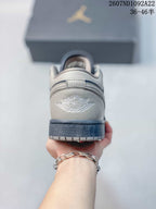 Rear view of a gray and navy low-top sneaker showing the embroidered Air Jordan wings logo and dark outsole.