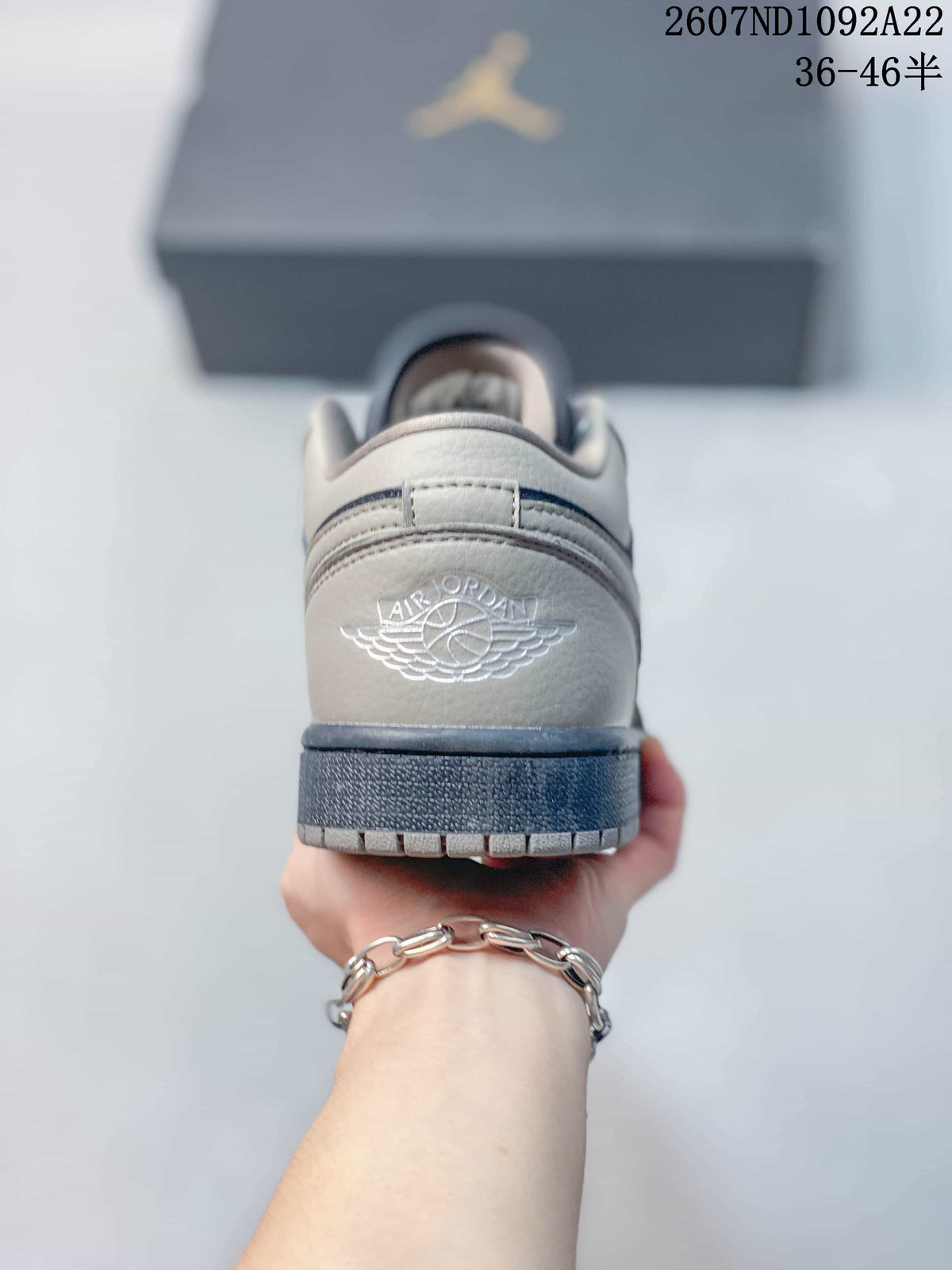Rear view of a gray and navy low-top sneaker showing the embroidered Air Jordan wings logo and dark outsole.