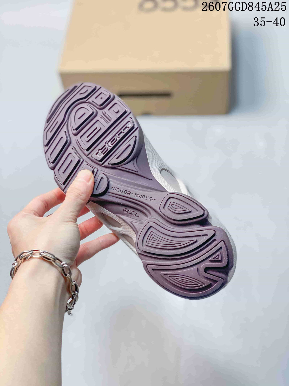 Underside of a white sneaker showing the sculpted purple-toned outsole with ECCO and BIOM branding.
