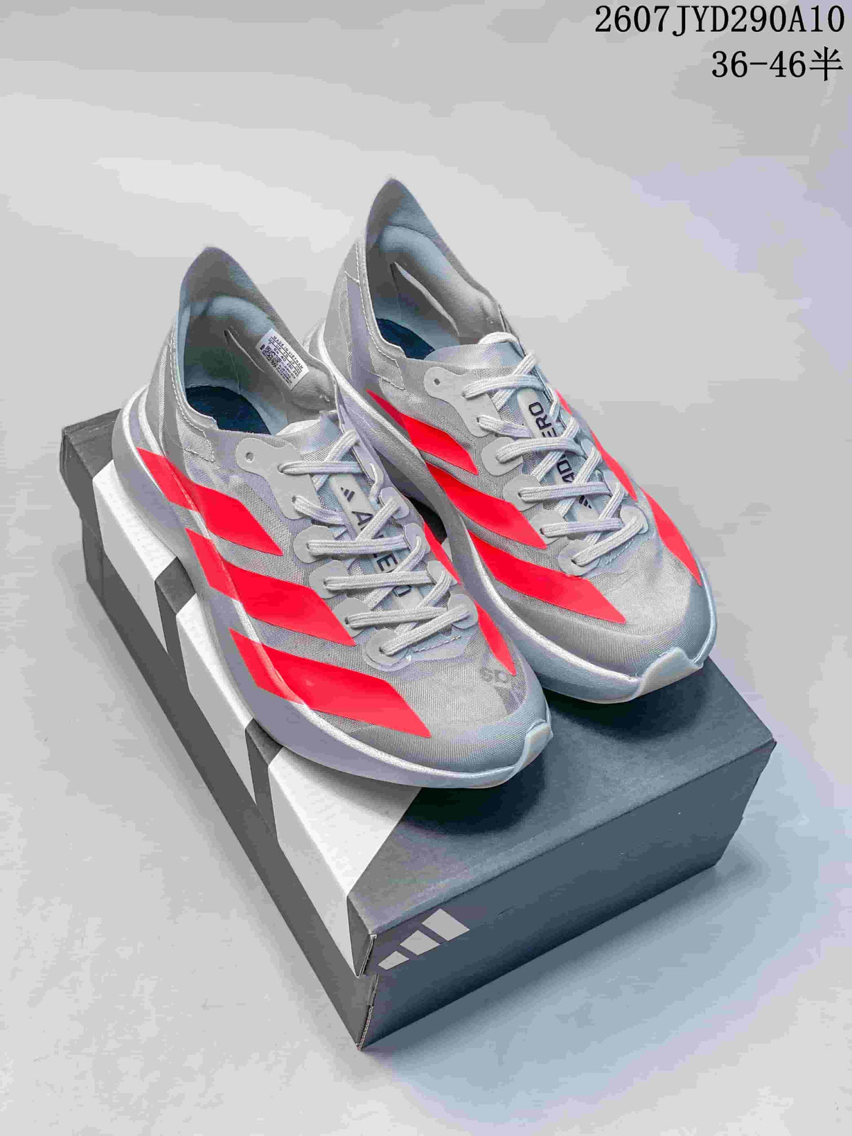 Pair of silver-gray Adidas Adizero Adios Pro Evo 2 running shoes with bright red accent panels displayed on a shoe box.