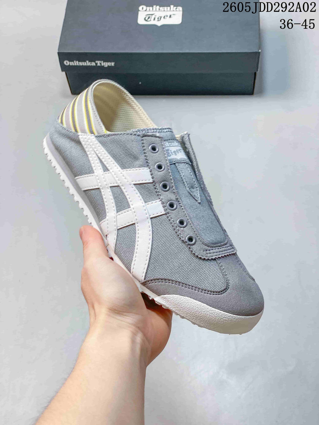 Three-quarter side view showing the gray slip-on sneaker, white side stripes, and rounded toe.