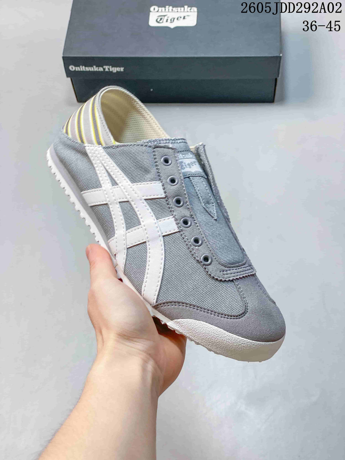 Three-quarter side view showing the gray slip-on sneaker, white side stripes, and rounded toe.