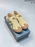 Pair of beige Onitsuka Tiger slip-on sneakers with green stripes and brown toe overlays displayed on a branded box; image text shows style code 2605JDD292A02 and size range 36–45.