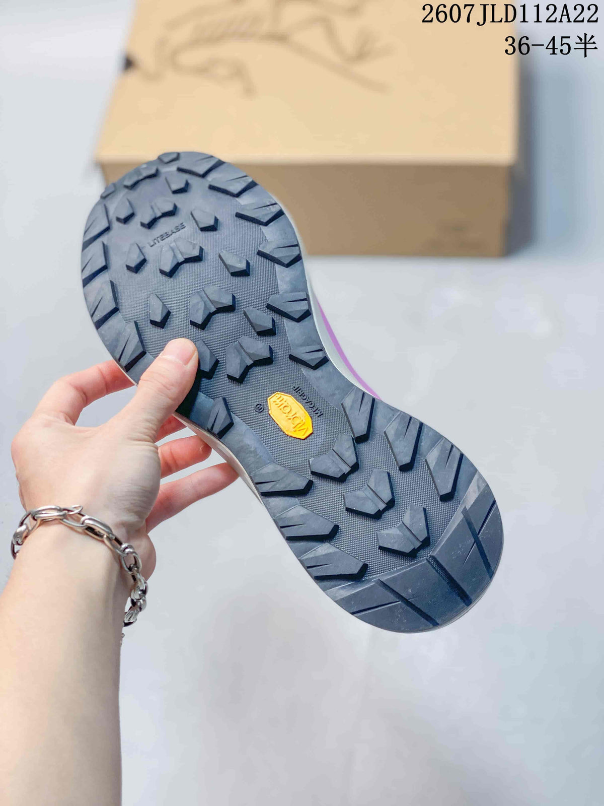Close-up of the dark outsole showing deep multidirectional lugs and a yellow Vibram mark.