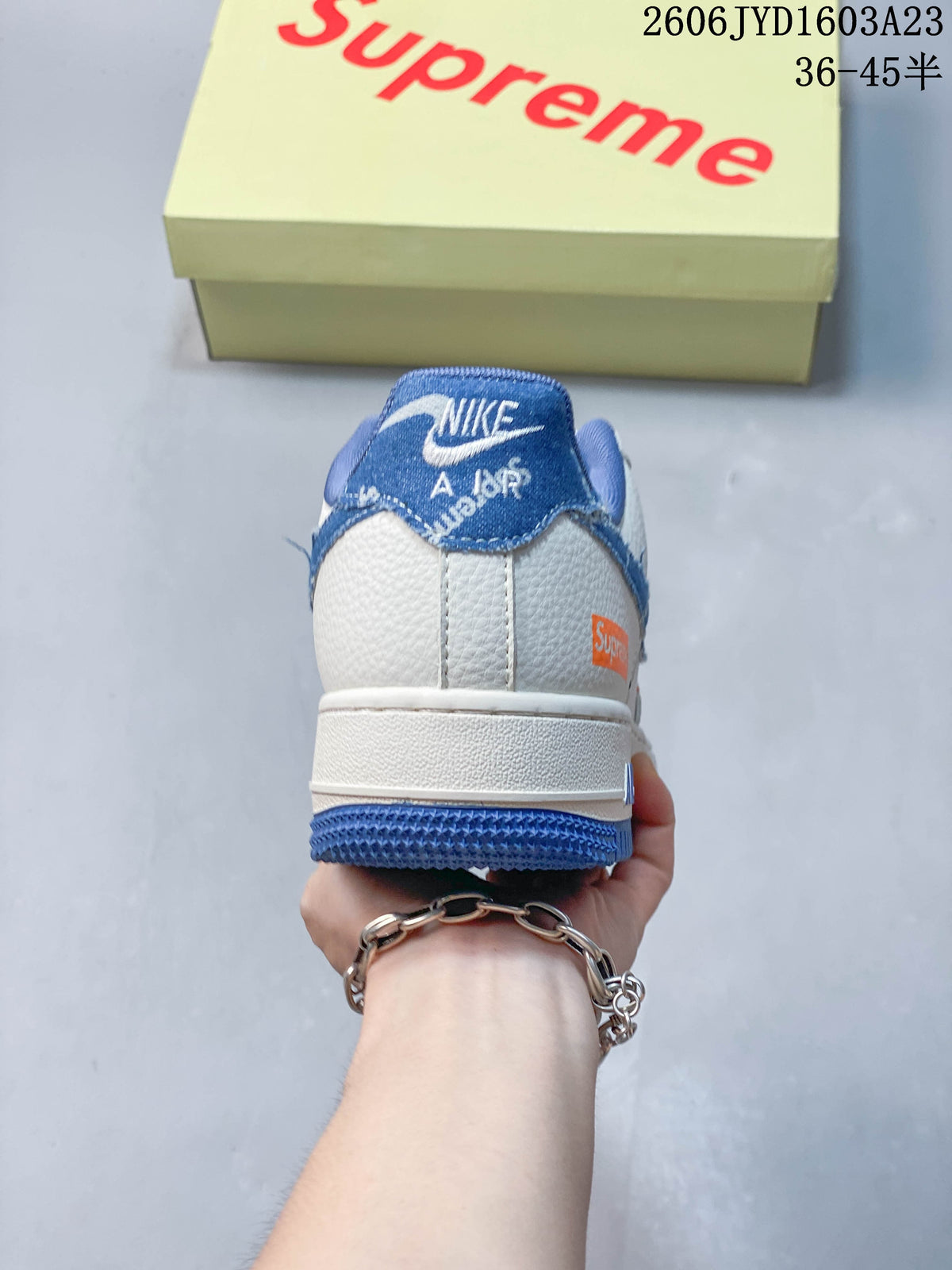 Rear view of the sneaker showing blue heel detailing and white upper