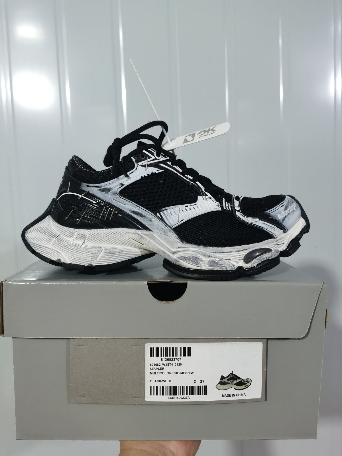 Pair of black-and-white sneakers displayed on a shoe box; the box label shows Stapler, model reference 0120, color BLACK/WHITE, and size C 37.
