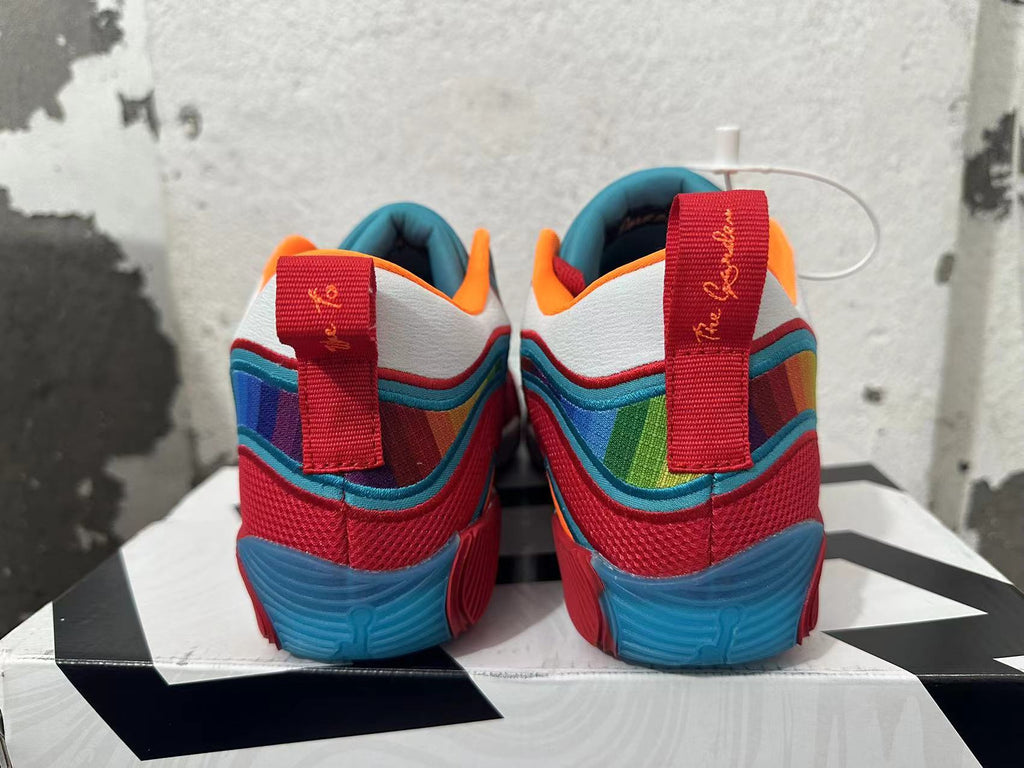Rear view of red Jordan basketball shoes with blue soles, multicolor panels and heel pull tabs.