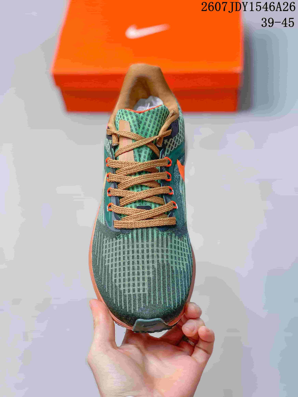 Top view of the green knit-style Nike running shoe with tan laces and orange lace accents.