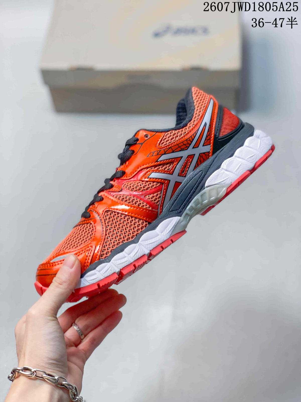 Side profile highlighting the ASICS branding, red-orange mesh upper, black overlays, and layered sole.