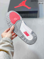 Bottom view of the sneaker showing a gray rubber outsole with red circular traction and raised red branding.