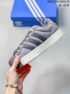 Side view of the grey sneaker showing the layered upper, three side stripes, shell toe, and raised sole.