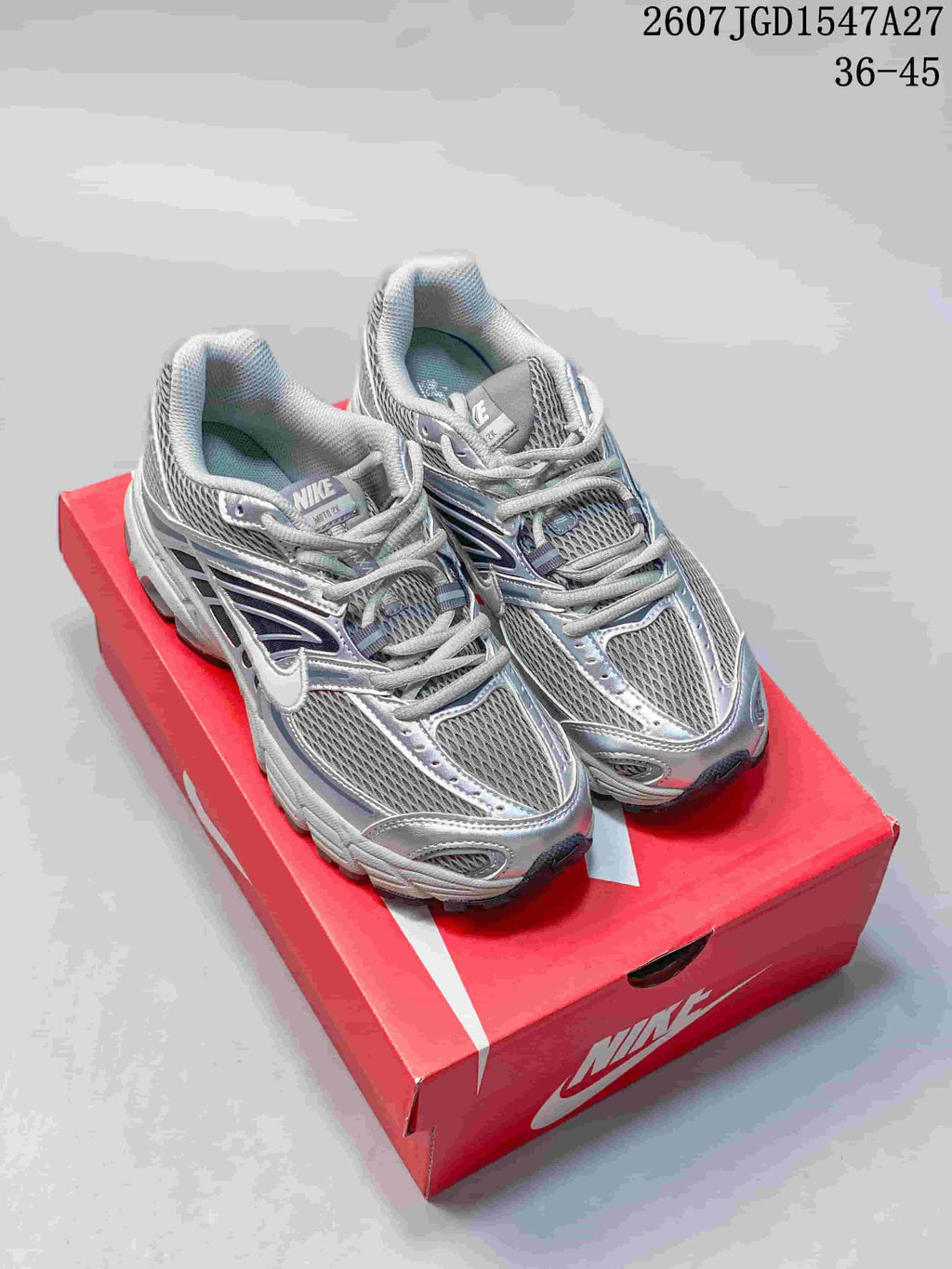 Pair of silver and grey Nike Air Max Moto 2K sneakers displayed on a red Nike shoebox.
