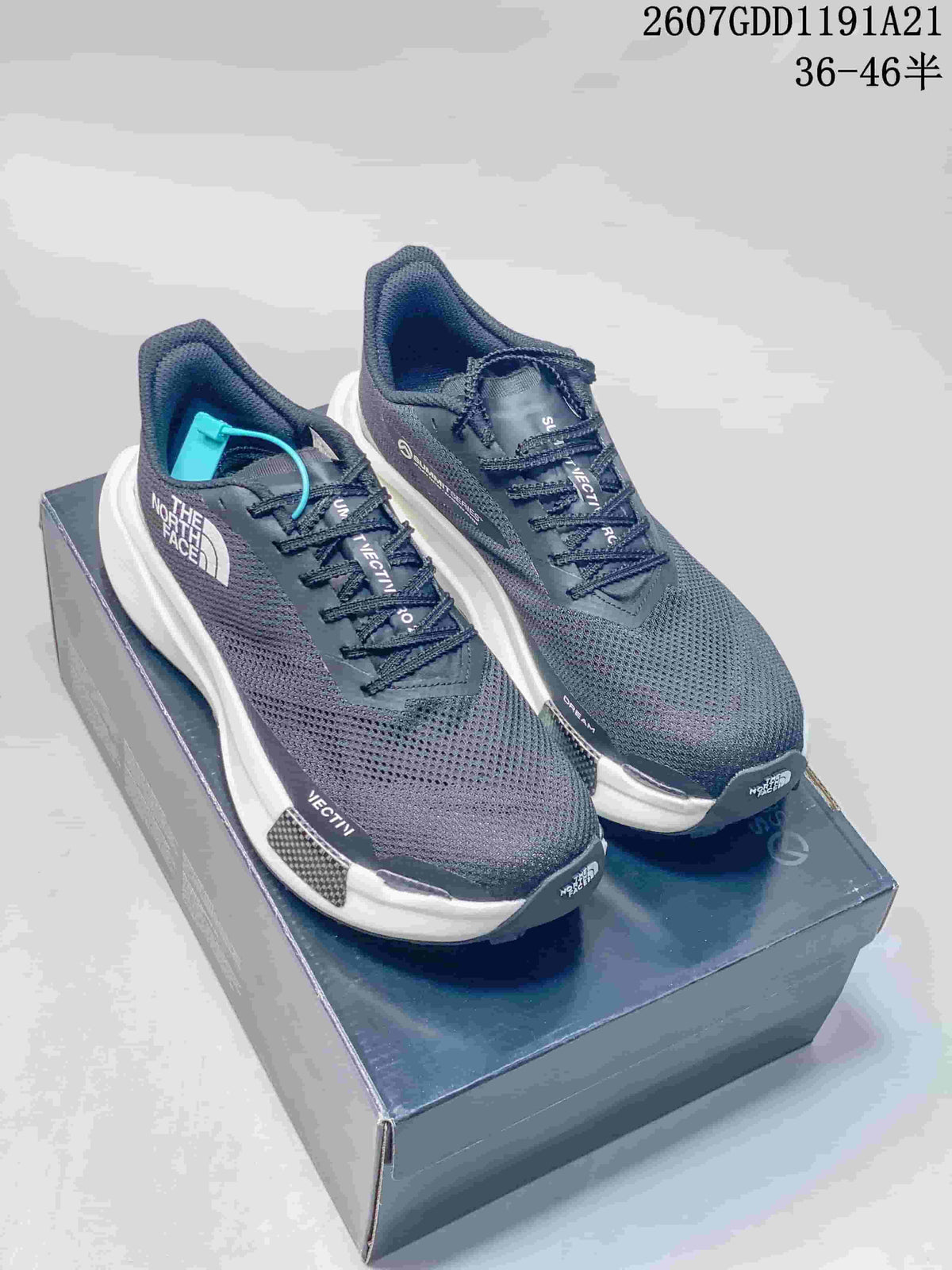 Pair of dark gray The North Face Summit sneakers displayed on a shoebox, showing the mesh uppers, white midsoles, and turquoise lace accent.