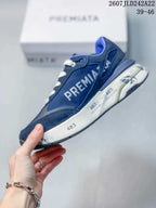 Side profile of a navy blue Premiata trainer showing layered panels, white side branding and printed midsole details.