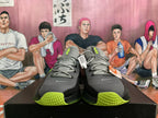 Front view of gray Nike low-top sneakers with black panels and lime-green details