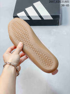 Underside of a pink Adidas sneaker showing its patterned gum-colored outsole
