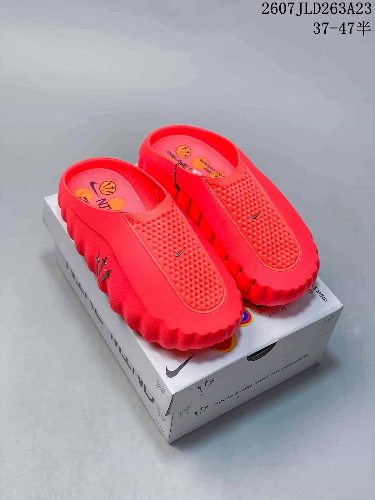 Bright red Nike Mind 001 slides displayed on a branded box, showing the perforated upper, textured footbed and thick scalloped sole.