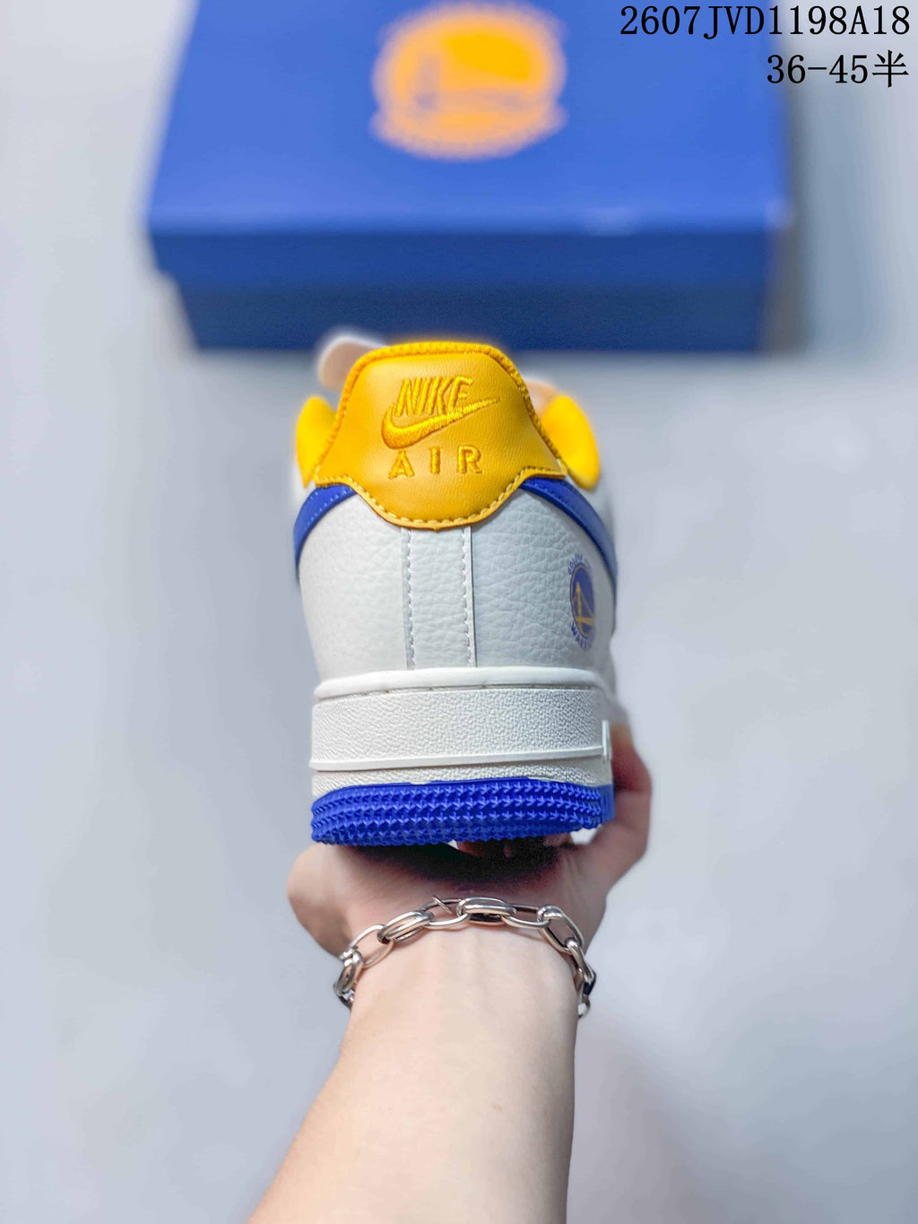 Rear view showing the yellow Nike Air heel tab, white upper, blue heel outsole, and side emblem.