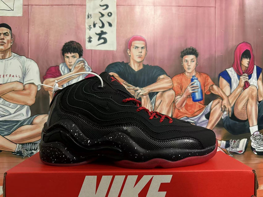 Side view of a black Nike basketball sneaker with layered wavy panels, red outsole and speckled midsole.