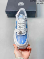 Top view showing white laces, perforated blue toe panel, white overlays, and AF1 lace hardware.