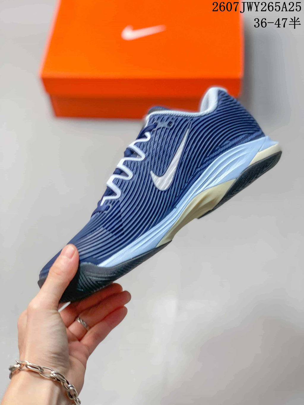 Side view of a navy and white Nike Vapor 12 tennis shoe showing the lace structure, side detailing, and outsole.