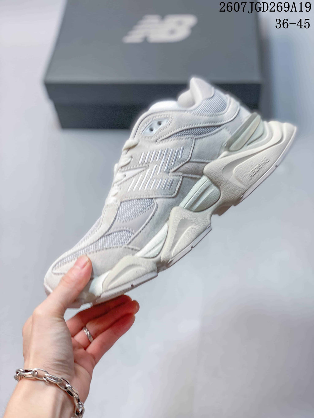 Side profile of a light white New Balance 9060 sneaker showing layered panels, mesh sections and a raised segmented sole.