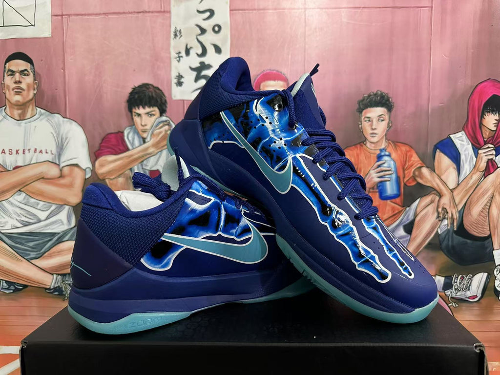Pair of navy and blue Nike Kobe basketball shoes shown at an angle, with aqua-colored outsoles