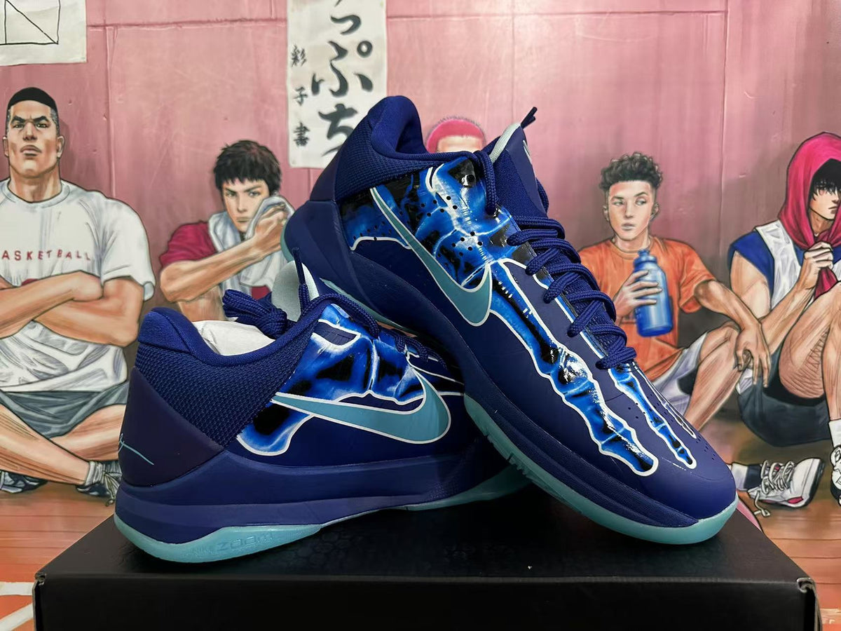Pair of navy and blue Nike Kobe basketball shoes shown at an angle, with aqua-colored outsoles