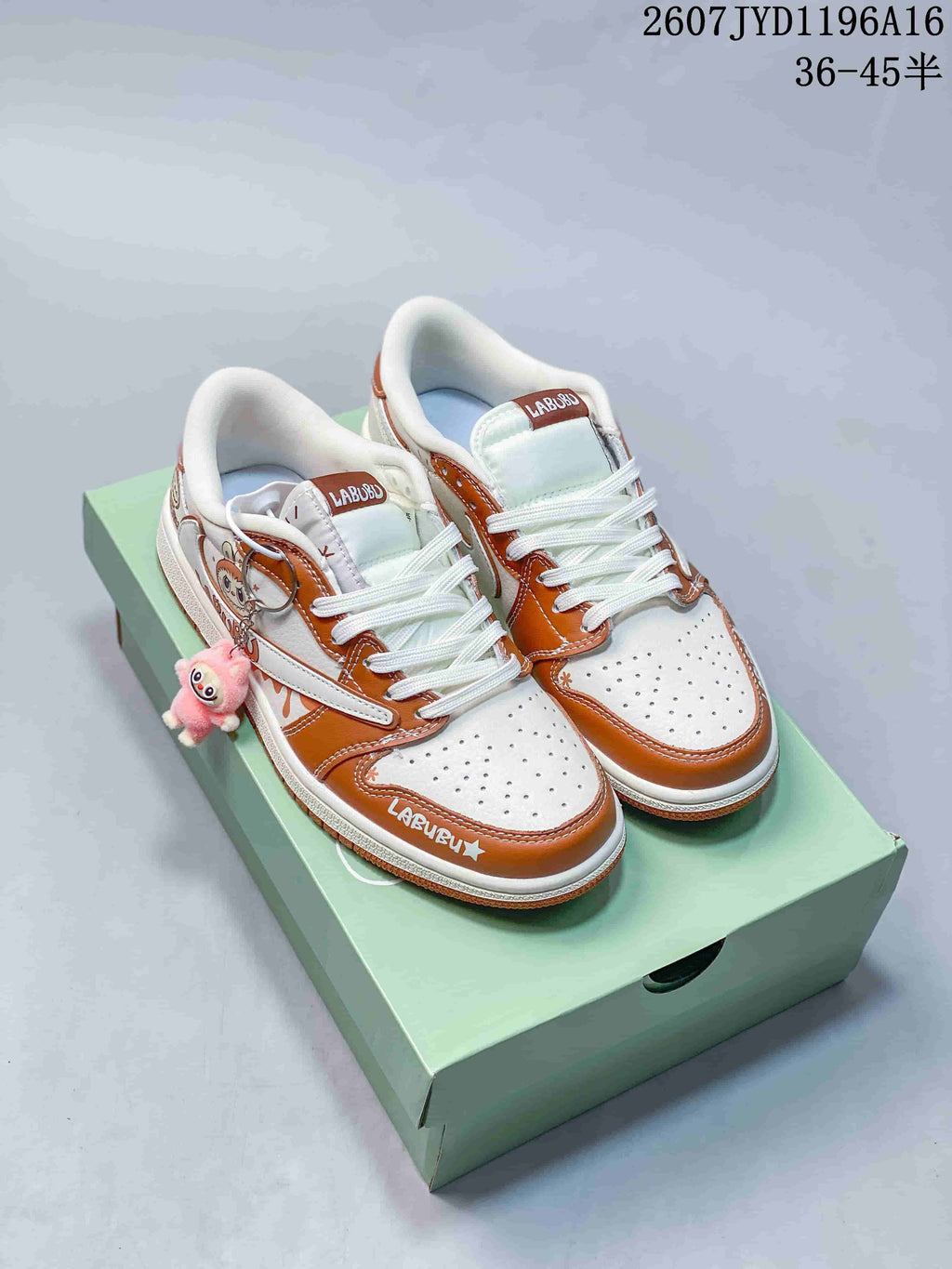 Pair of white and brown low-top Jordan sneakers with Labubu details displayed on a green shoebox.