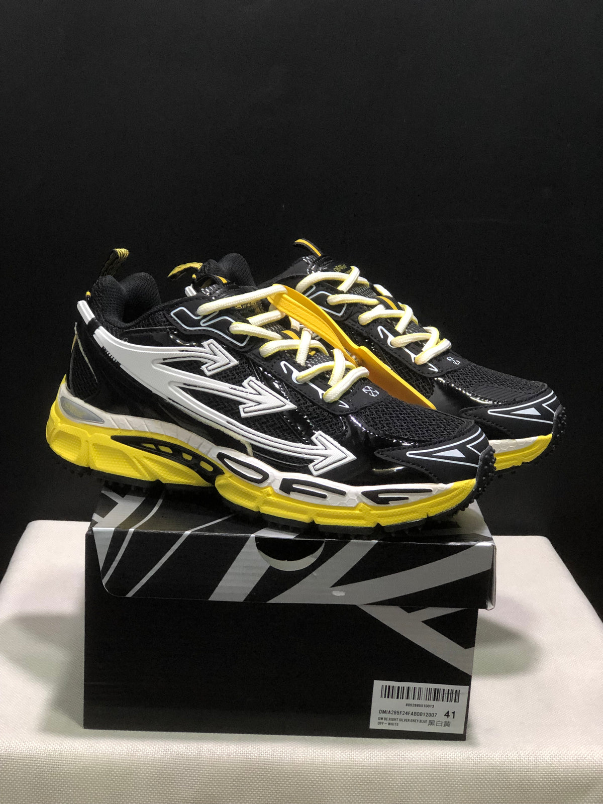 Pair of black, white, and yellow Off-White Be Right Back sneakers displayed on a branded box.
