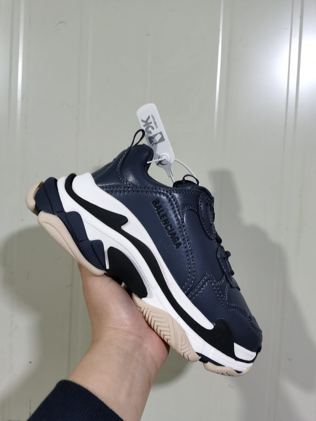 Angled view of a Balenciaga Triple S sneaker with visible side branding, layered sole construction, and beige-toned outsole.