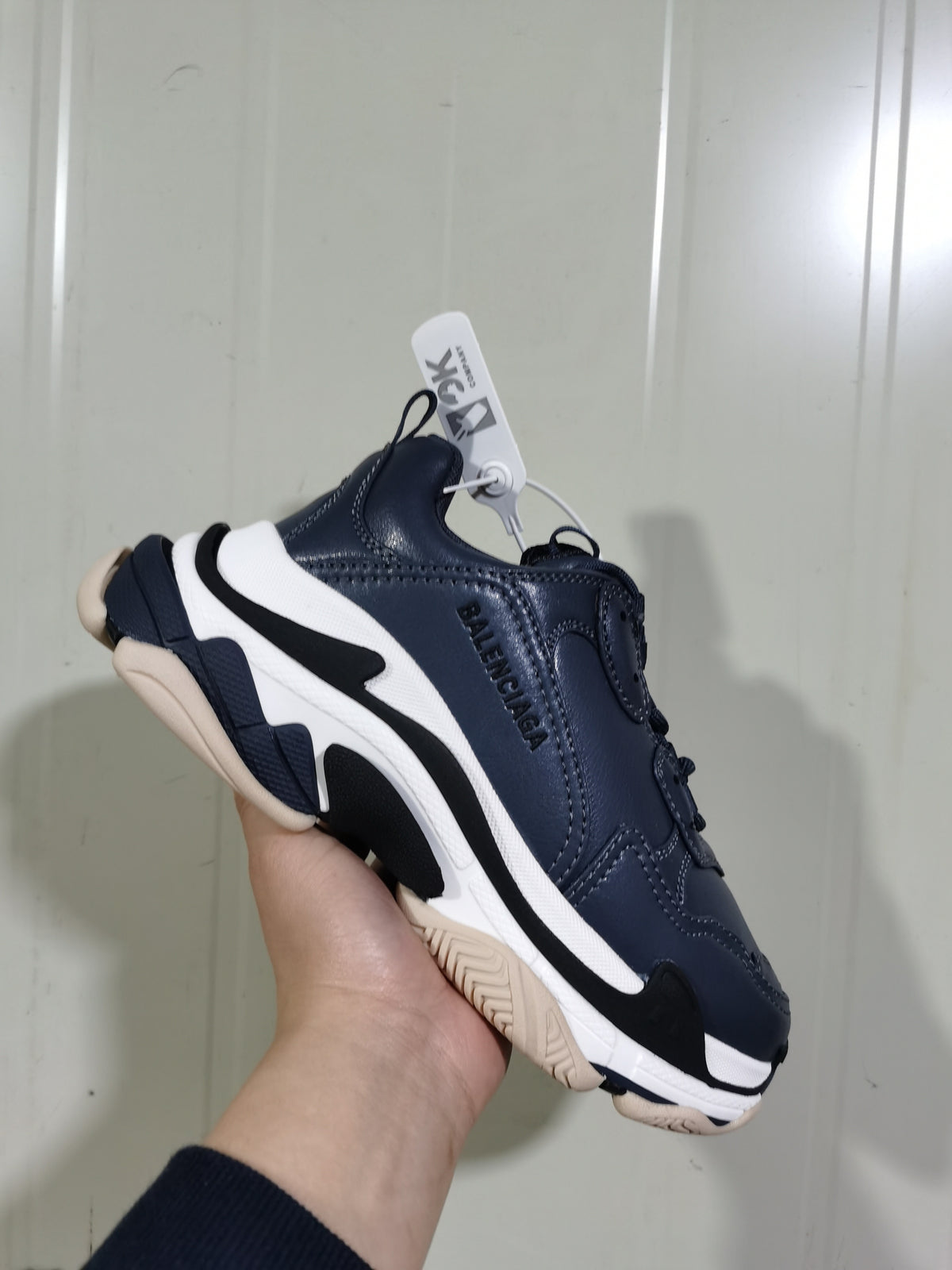 Angled view of a Balenciaga Triple S sneaker with visible side branding, layered sole construction, and beige-toned outsole.