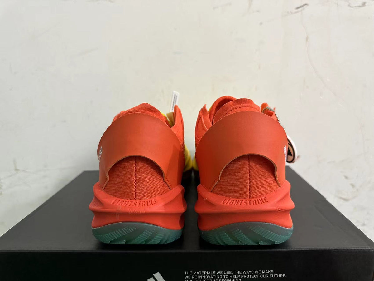 Rear view of yellow and orange Adidas Adizero shoes with teal outsole accents