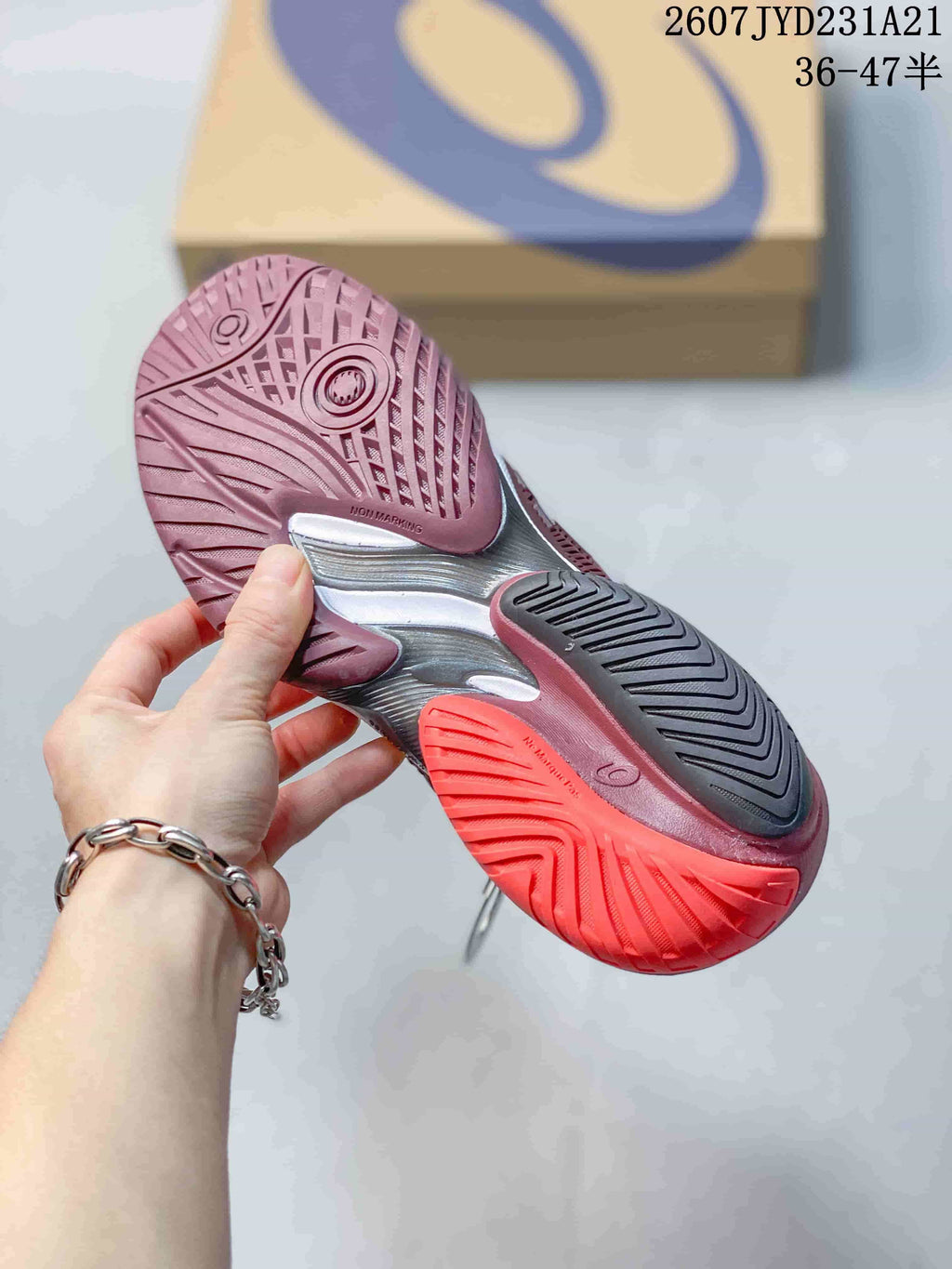 Bottom view of the burgundy tennis shoe showing the patterned rubber outsole and contrasting red, black, and silver sections.