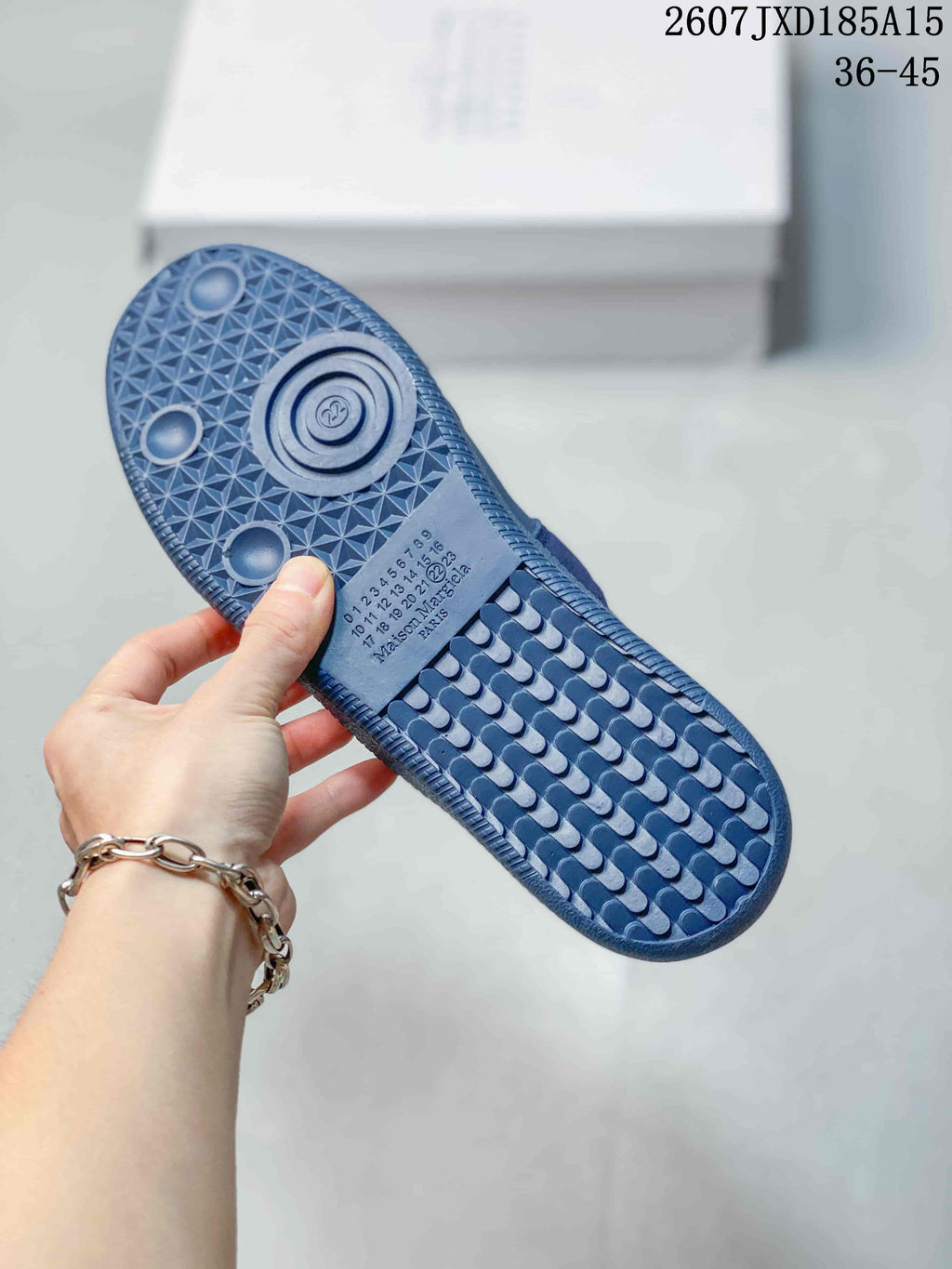 Blue sneaker outsole showing a geometric tread pattern, circular details, and visible Maison Margiela PARIS text.