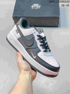 Close-up of a white, gray and black Nike Air Force 1-style sneaker with dark laces, contrast panels and a dark outsole.