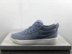 Side view of a blue-gray Nike Book 1 shoe with a textured side panel and light-colored midsole.