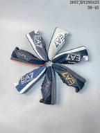 Several Emporio Armani EA7 low-top sneakers arranged in a circle, showing navy, black, gray and white-based colorways; image text shows style code 2607JDY295A25 and EU size range 39–45.