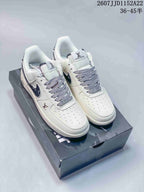 Pair of white low-top sneakers with dark navy patterned side panels, displayed on a shoebox; size range text and style code are visible at the top right.