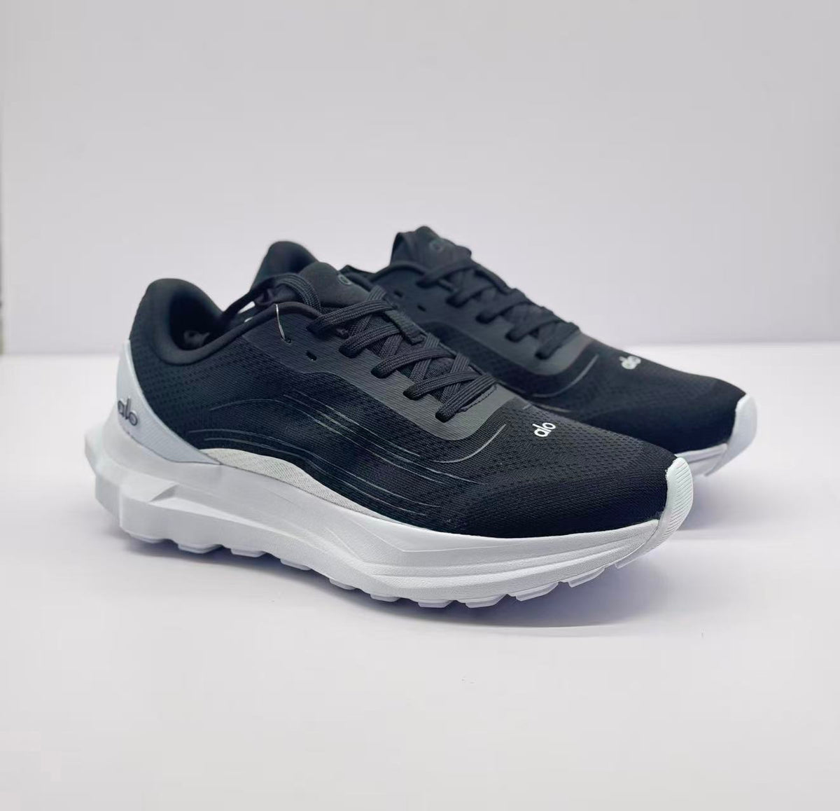 Three-quarter front view of the black and white Alo runner sneakers.