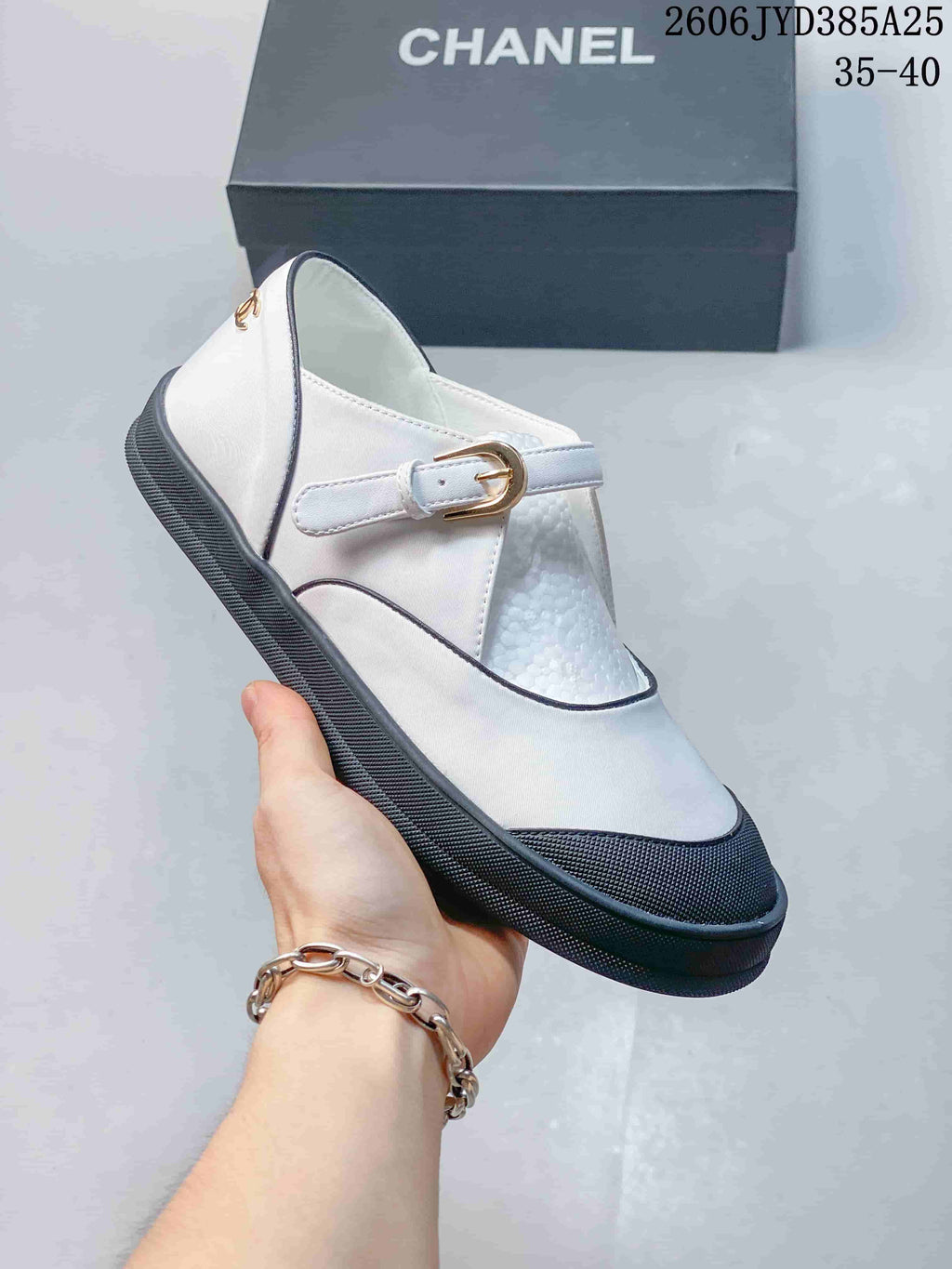 Side view of a white Mary Jane flat showing its buckle strap, contrast piping, and dark sole.